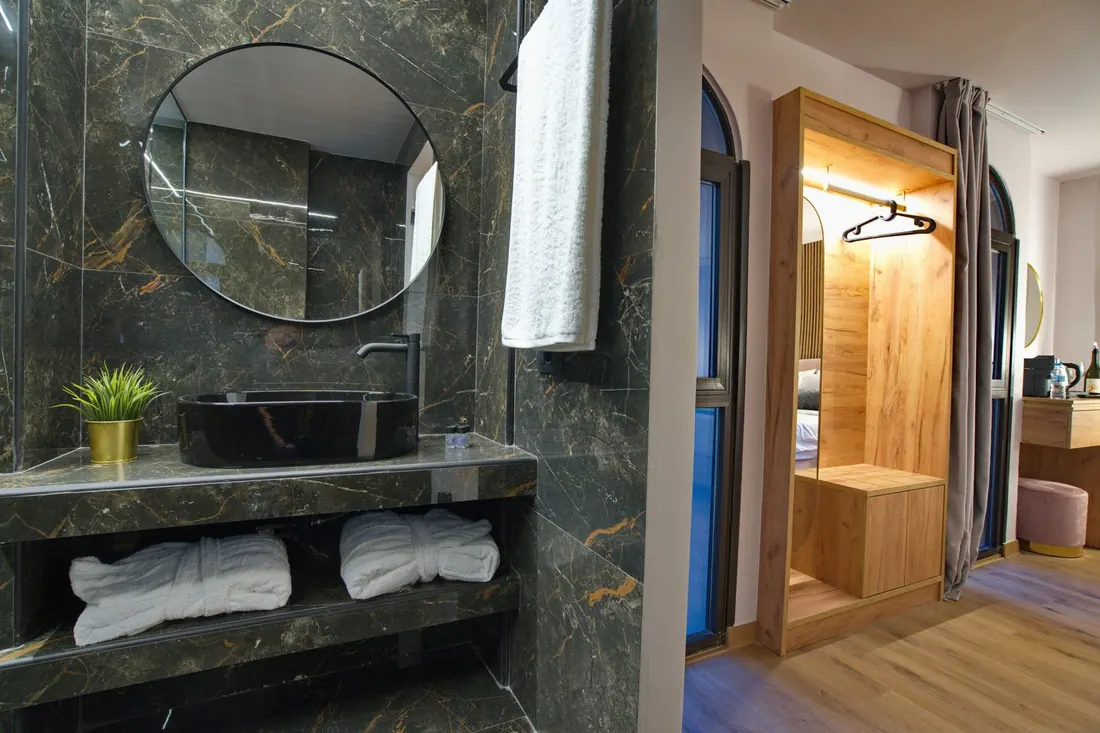 A marble bathroom with a round mirror