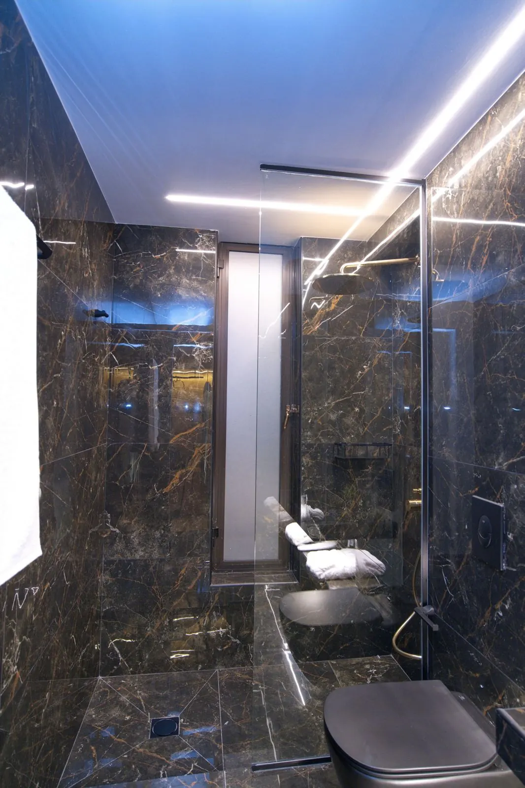 A dark marble bathroom with a glass shower